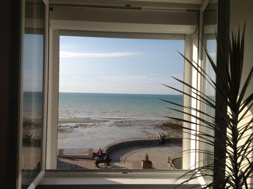 een raam met uitzicht op het strand vanuit een gebouw bij Blanc d'ecume in Ault