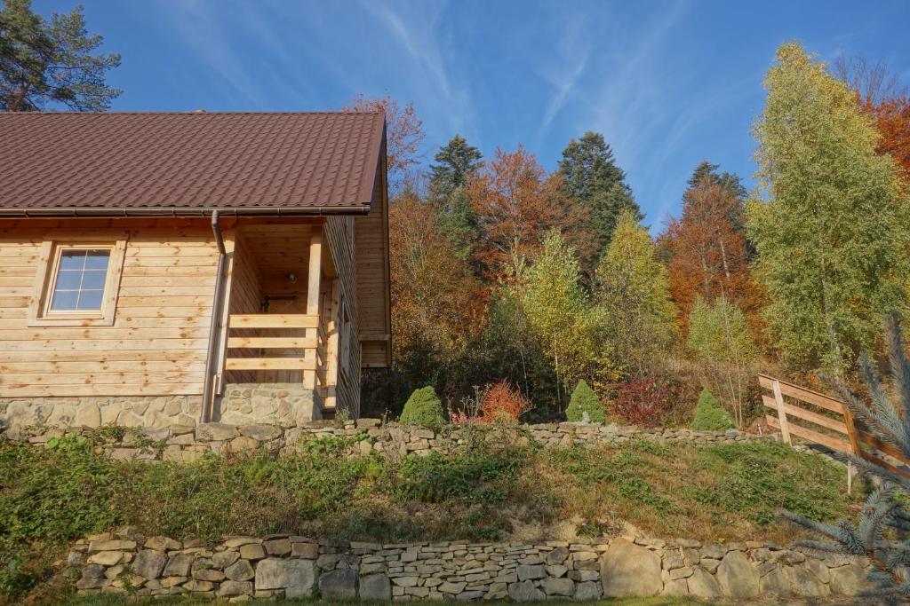 Eine Blockhütte mit einer steinernen Stützmauer und Bäumen in der Unterkunft Bukowinka in Krempna