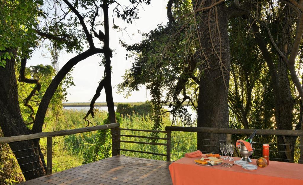 a table sitting on a wooden deck near a tree at Chobe River Cottages in Kasane
