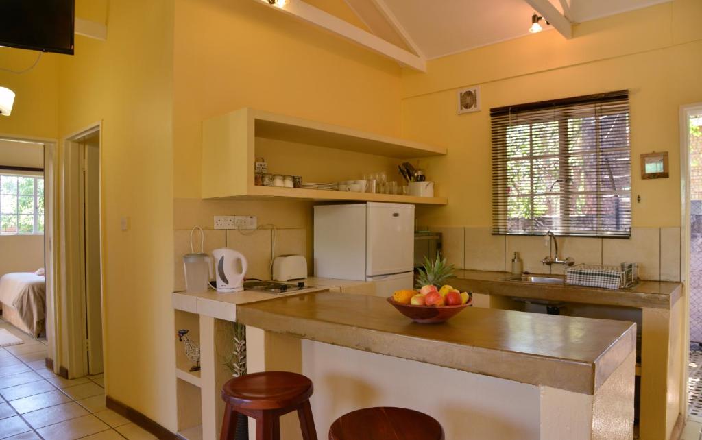 a kitchen with yellow walls and a counter with a bowl of fruit at Chobe River Cottages in Kasane