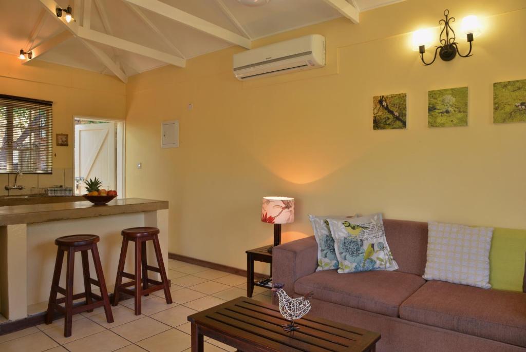 a living room with a couch and a kitchen at Chobe River Cottages in Kasane