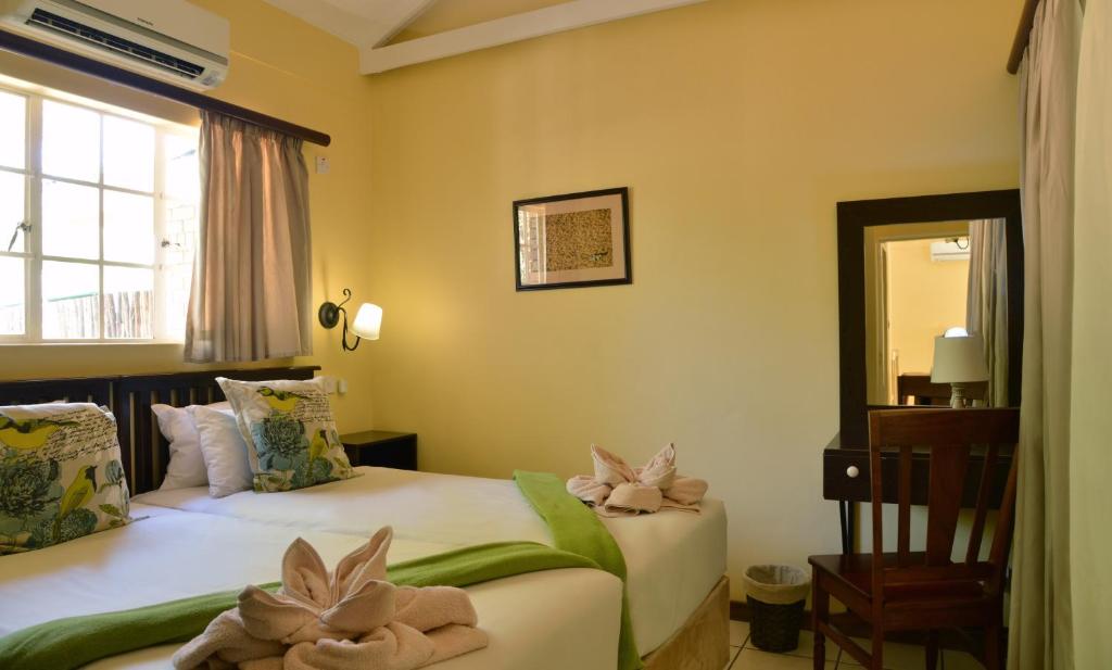 two beds in a room with two stuffed animals on them at Chobe River Cottages in Kasane
