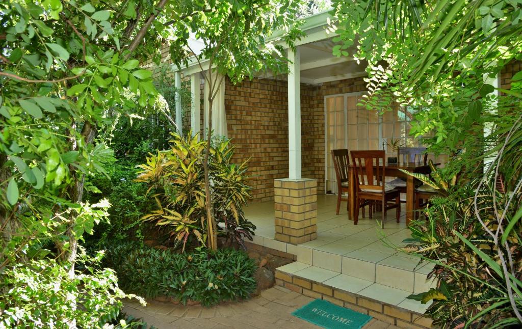 a patio with a table and chairs and trees at Chobe River Cottages in Kasane