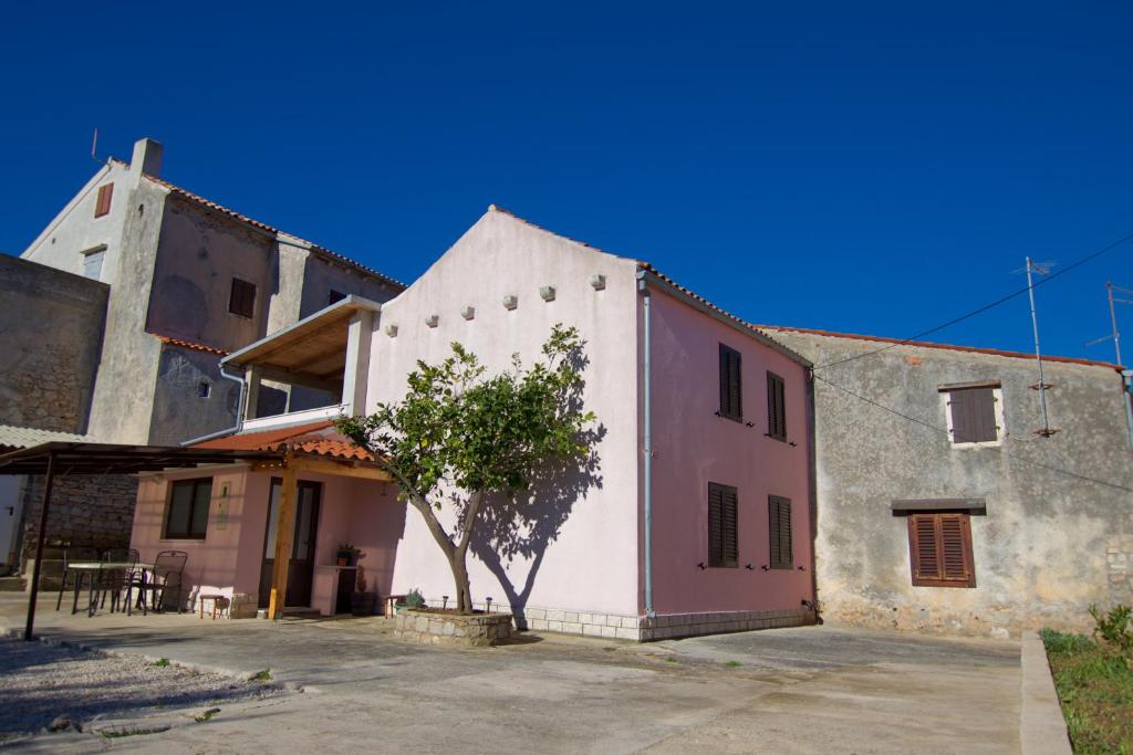 a white and pink building with a tree in front at Apartment Alen in Veli Lošinj