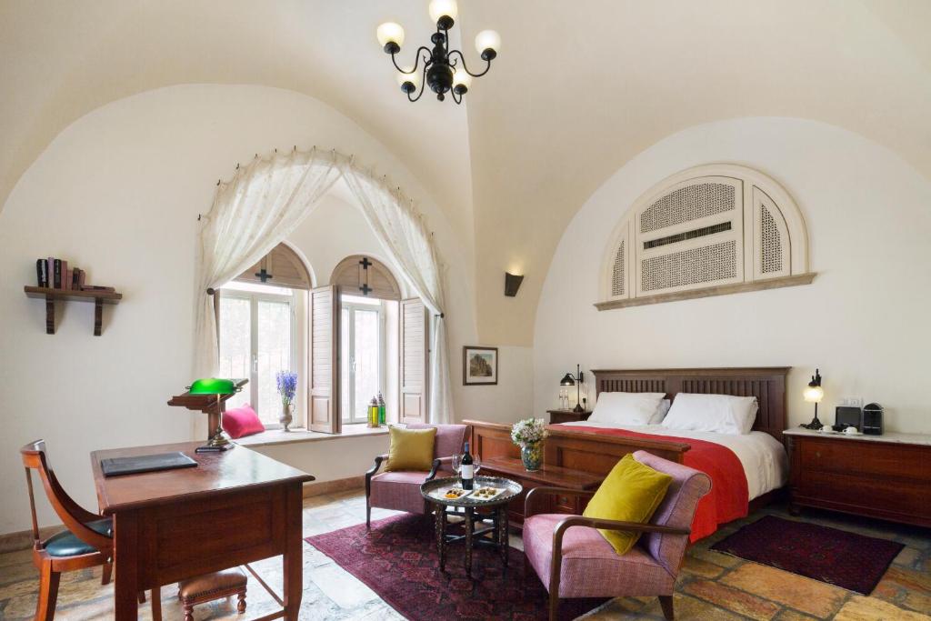 a bedroom with a bed and a desk and chairs at The American Colony Hotel - Small Luxury Hotels of the World in Jerusalem