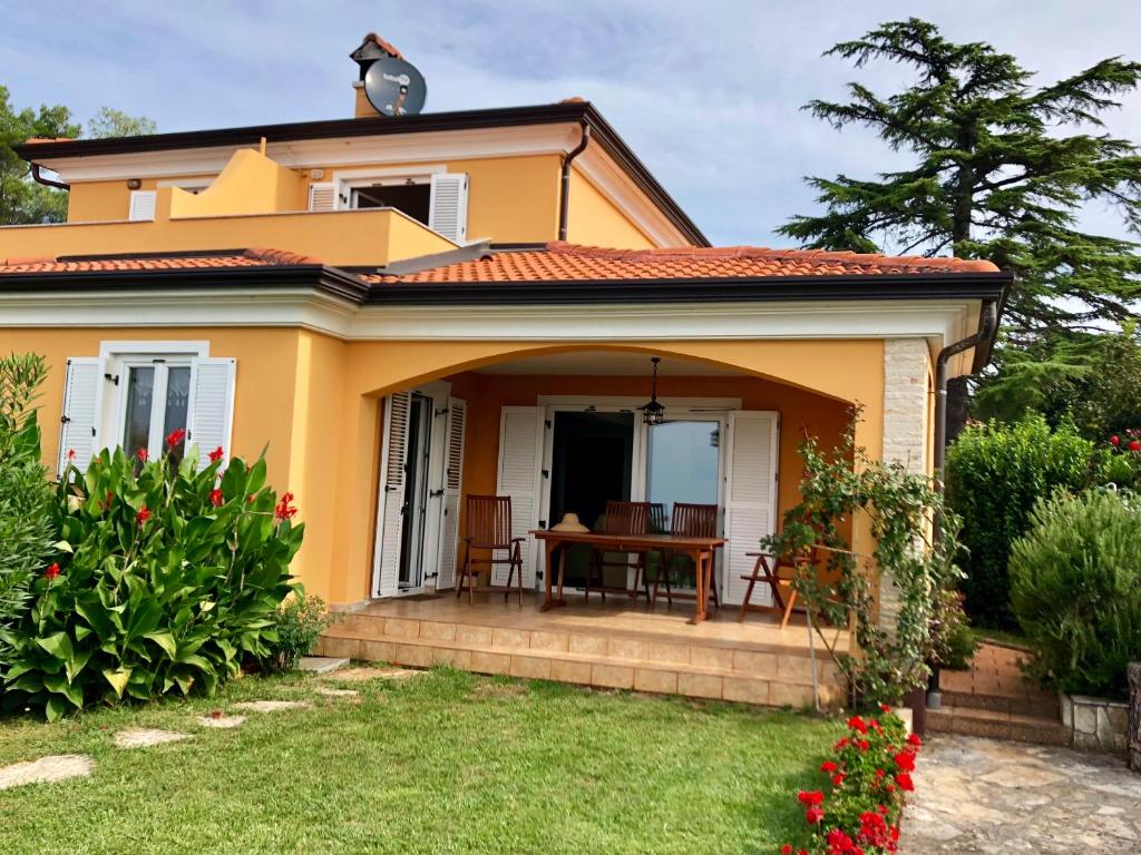 una pequeña casa amarilla con una mesa en el patio en Villa Maya, en Umag