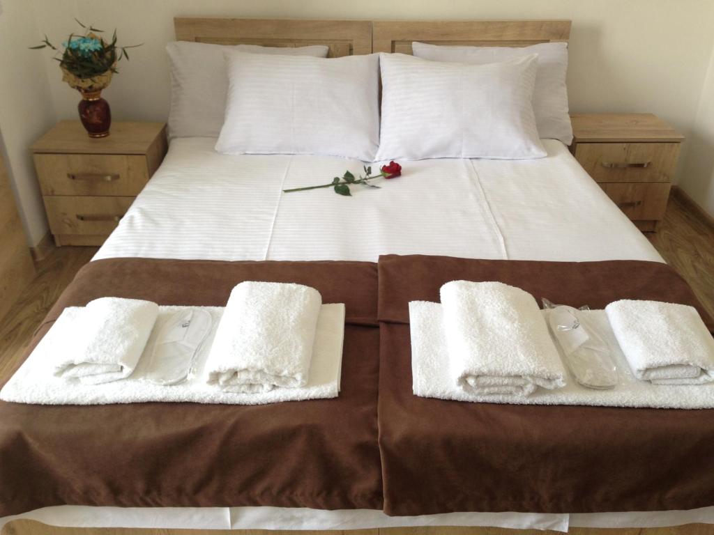 a bed with white towels and a red flower on it at Hotel Continental in Gori