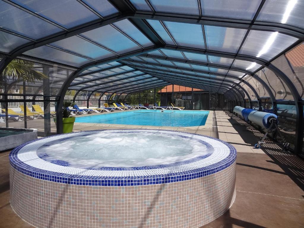 a swimming pool with a large hot tub in a building at Camping le Rouge Gorge **** 10' Puy du Fou in Saint-Laurent-sur-Sèvre