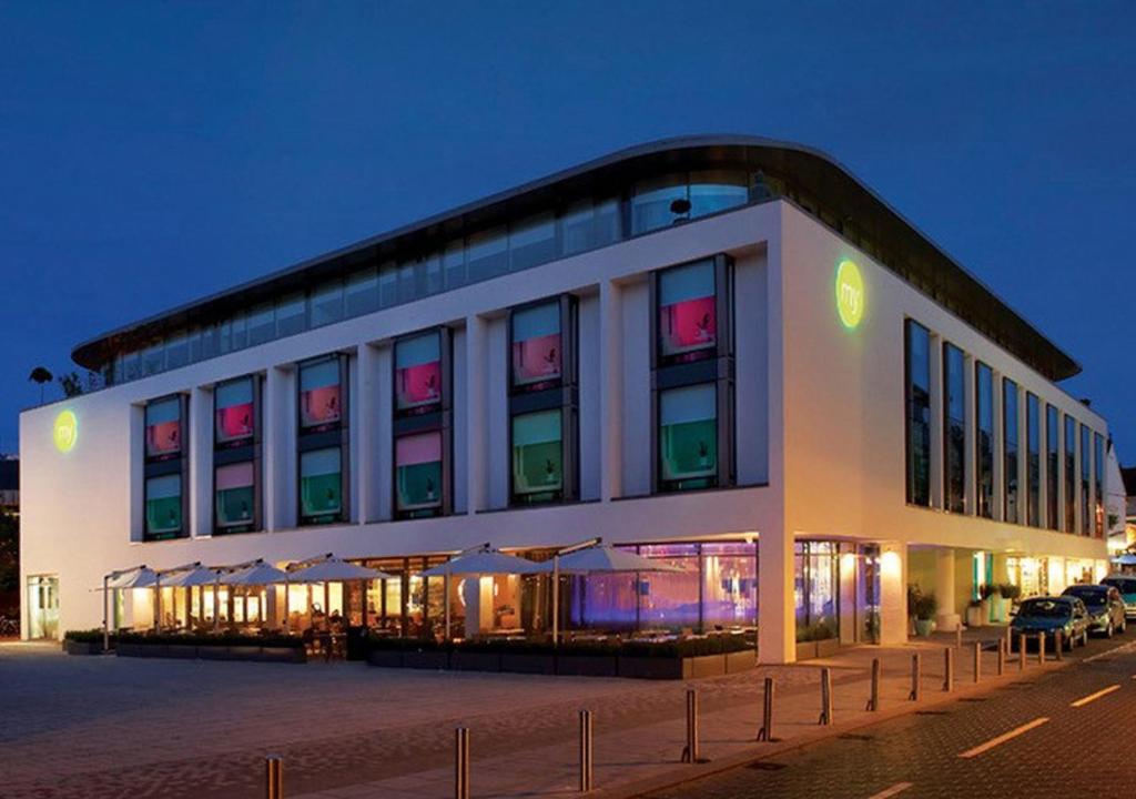 un grand bâtiment blanc avec des tables et des parasols la nuit dans l'établissement My Brighton, à Brighton et Hove