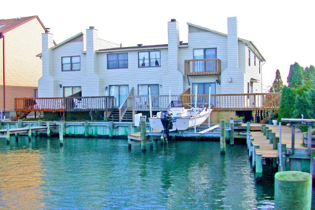 a house and a boat on the water next to a dock at Sea Jay Townhouse 616C in Ocean City