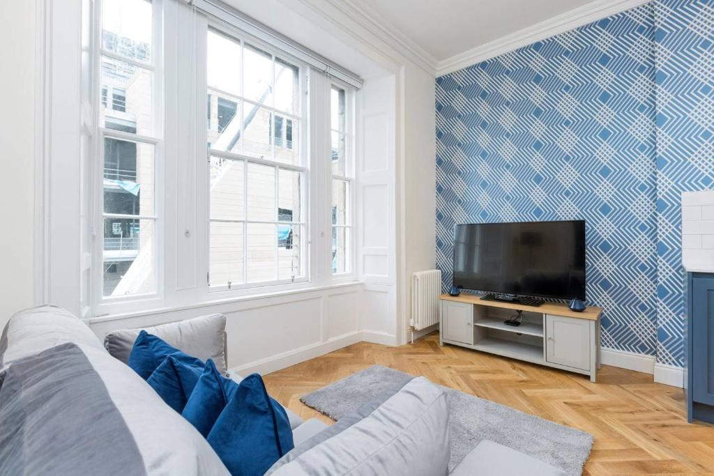 uma sala de estar com um sofá e uma televisão de ecrã plano em Luxury Renovated 1 Bed Nr St James - Super Central em Edimburgo