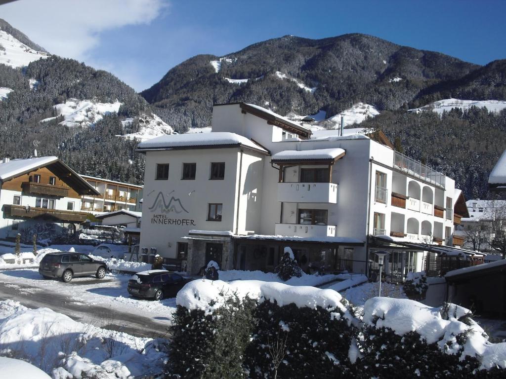 un edificio nella neve con montagne sullo sfondo di Hotel Innerhofer a Gais