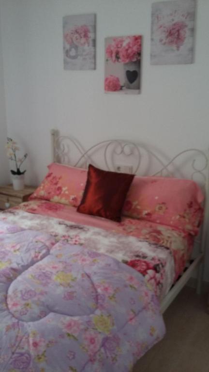 1 cama con edredón rosa y almohadas en El Campello DEBORAH, en El Campello