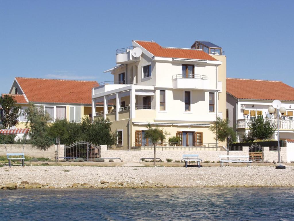 duży biały budynek z ławkami przed wodą w obiekcie Villa Ivana B&B w mieście Zadar