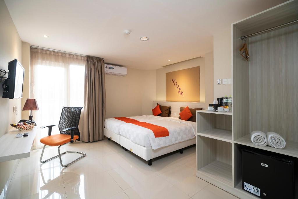 a bedroom with a bed and a desk and a chair at The Gloria Suites Grogol in Jakarta
