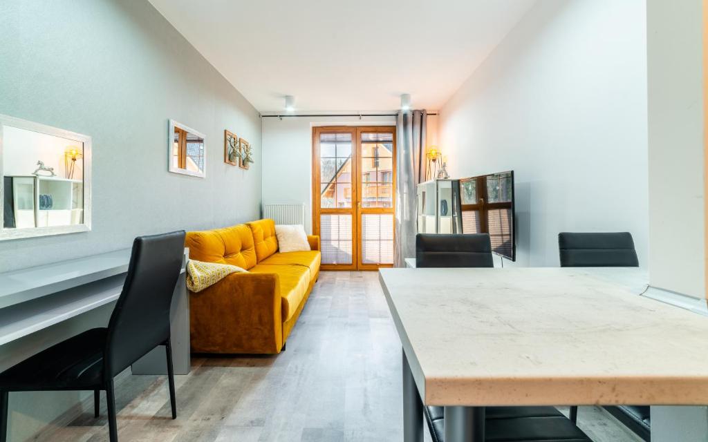 salon z żółtą kanapą i stołem w obiekcie Apartamenty EverySky Nadrzeczna 3E-3D w mieście Karpacz