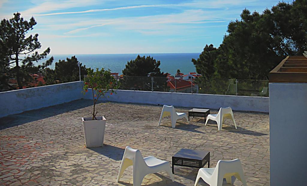 a group of white chairs and a table and a potted plant at Residencia Praia Norte - AL in Nazaré