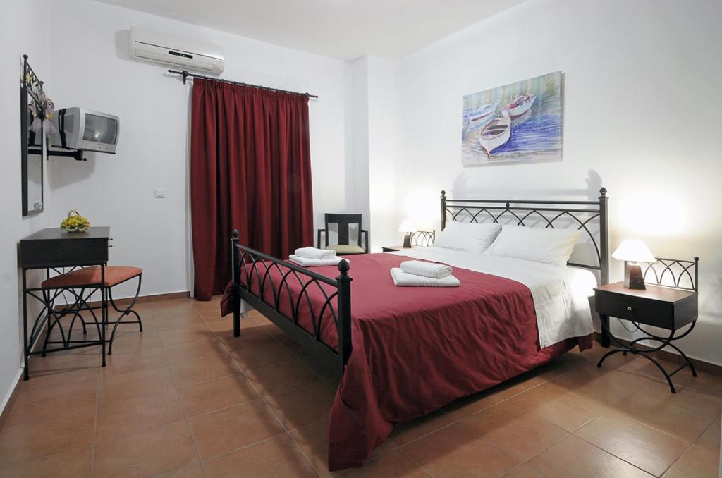 a bedroom with a large bed with a red blanket at Kythera Golden Sun in Agia Pelagia Kythira