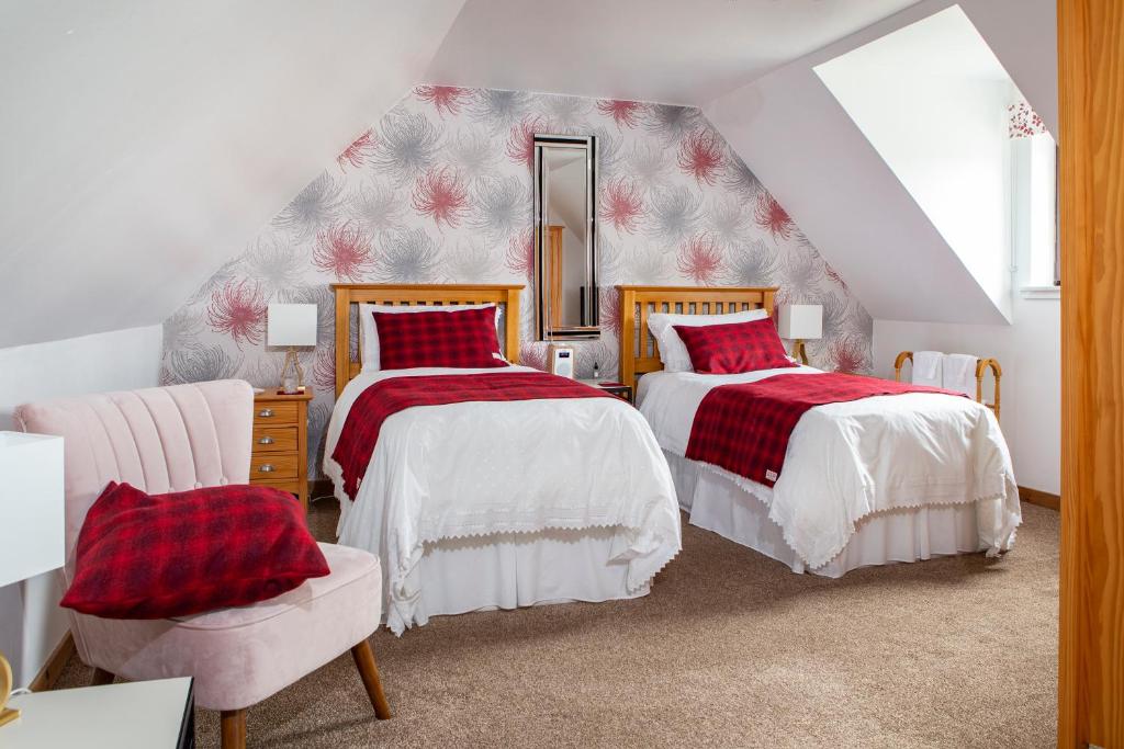 a attic bedroom with two beds and a chair at Ceol na Mara Guest House in Tarbert