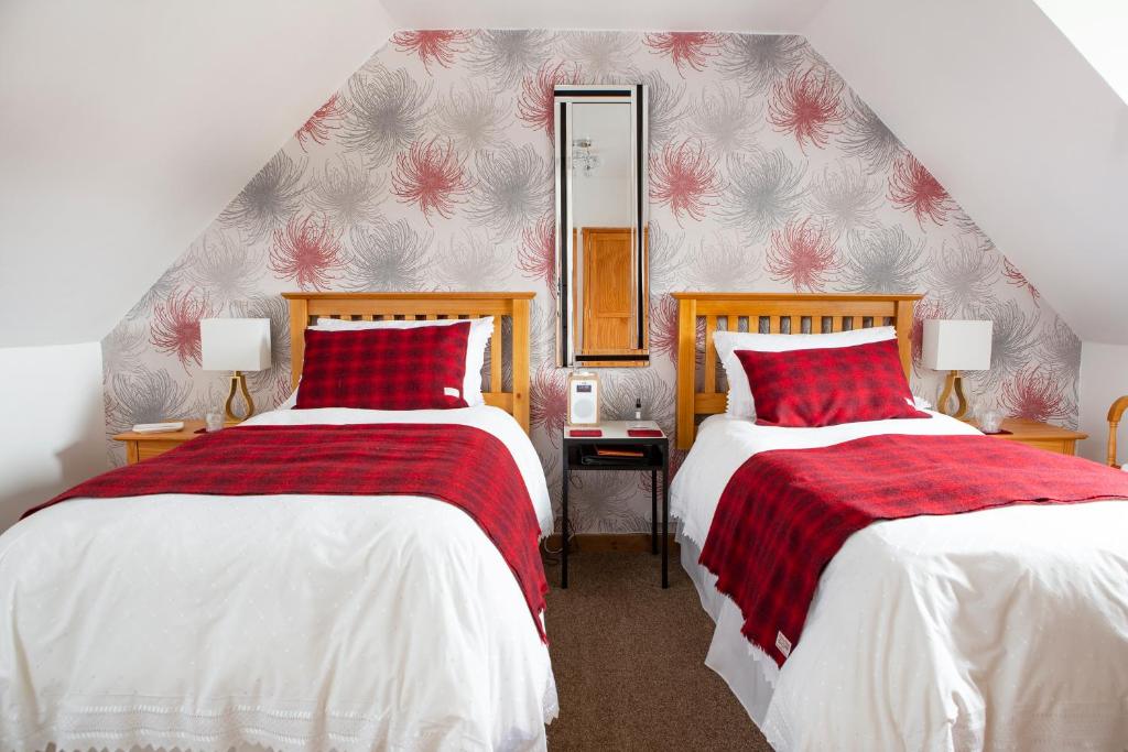 a bedroom with two beds and a mirror on the wall at Ceol na Mara Guest House in Tarbert