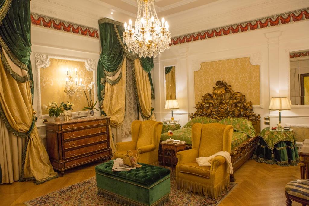 a bedroom with a bed and chairs and a chandelier at Grand Hotel Majestic gia' Baglioni in Bologna