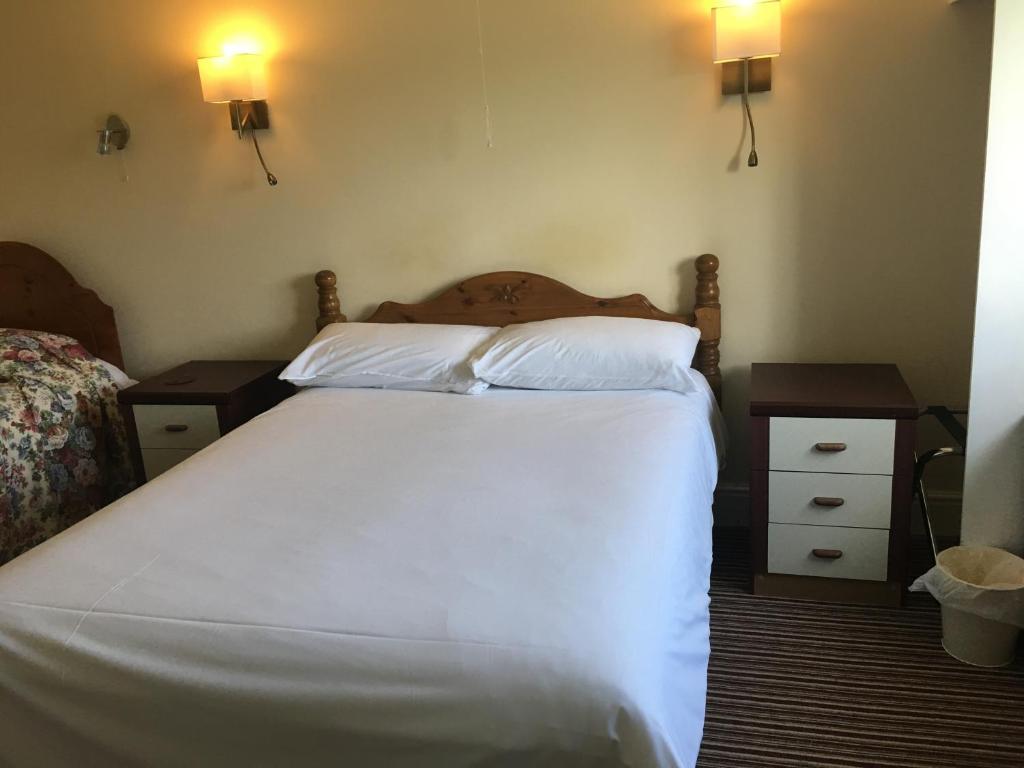 Swinderby的住宿－HALFWAY FARM MOTEL，一间卧室配有白色床和2个床头柜