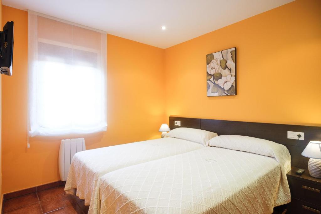 1 dormitorio con 1 cama con paredes de color naranja y ventana en Apartamentos de Herminia, en Manzaneda