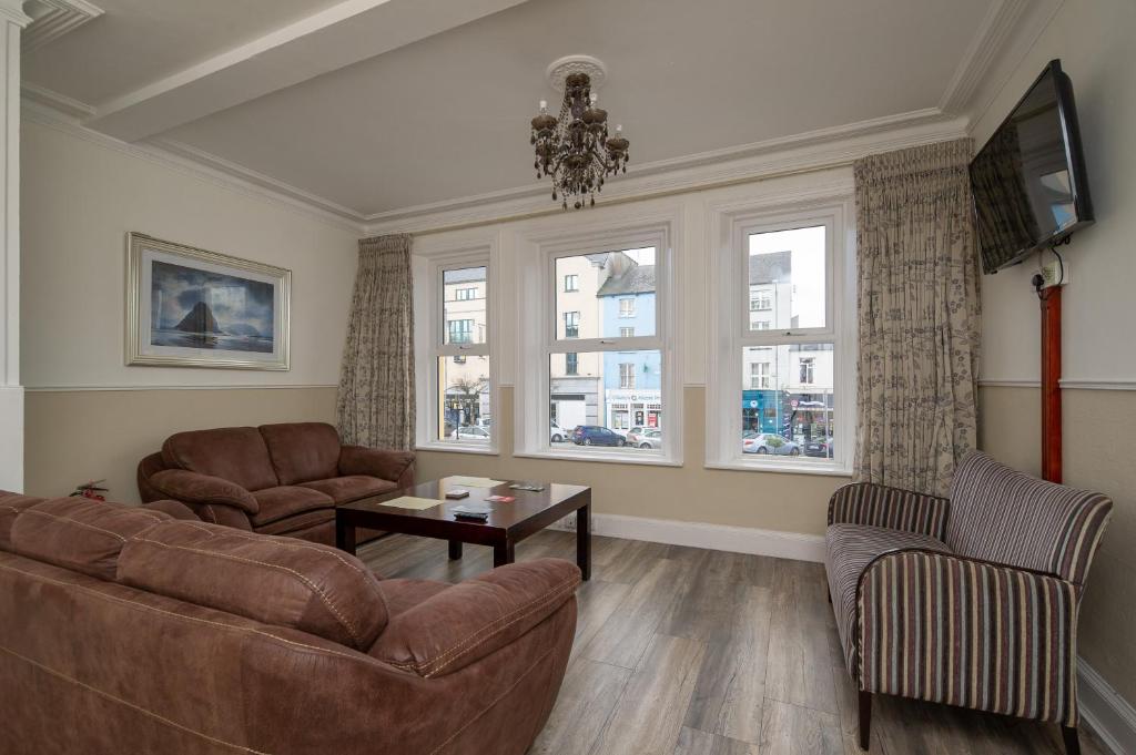 a living room with a couch and chairs and windows at The Square townhouse Fermoy in Fermoy