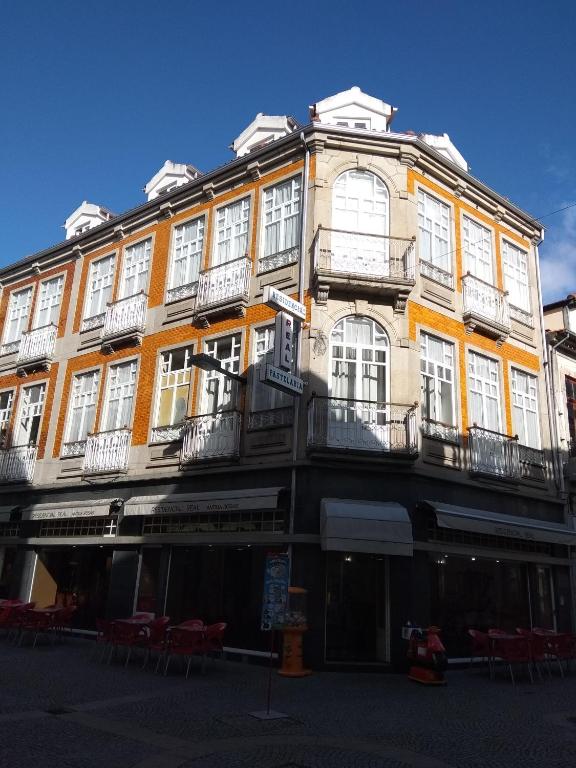 Un gran edificio amarillo con ventanas blancas en una calle. en Residencial Real - Antiga Rosas, en Vila Real