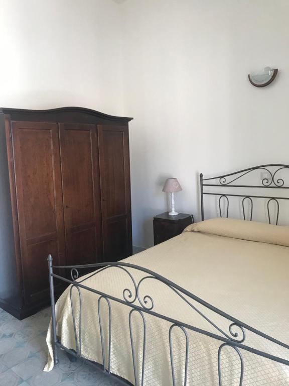 a bedroom with a bed and a wooden cabinet at Casa Cardi in Sperlonga
