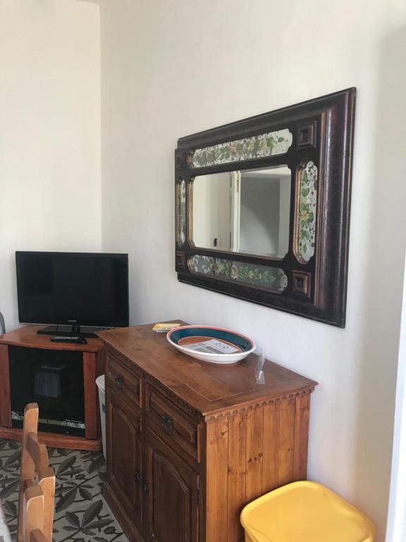 a mirror on a wall next to a desk with a yellow stool at Casa Cardi in Sperlonga