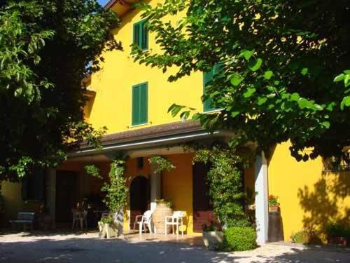 Ein gelbes Haus mit zwei Katzen, die draußen sitzen. in der Unterkunft Agriturismo La Cantina in Bastia Umbra