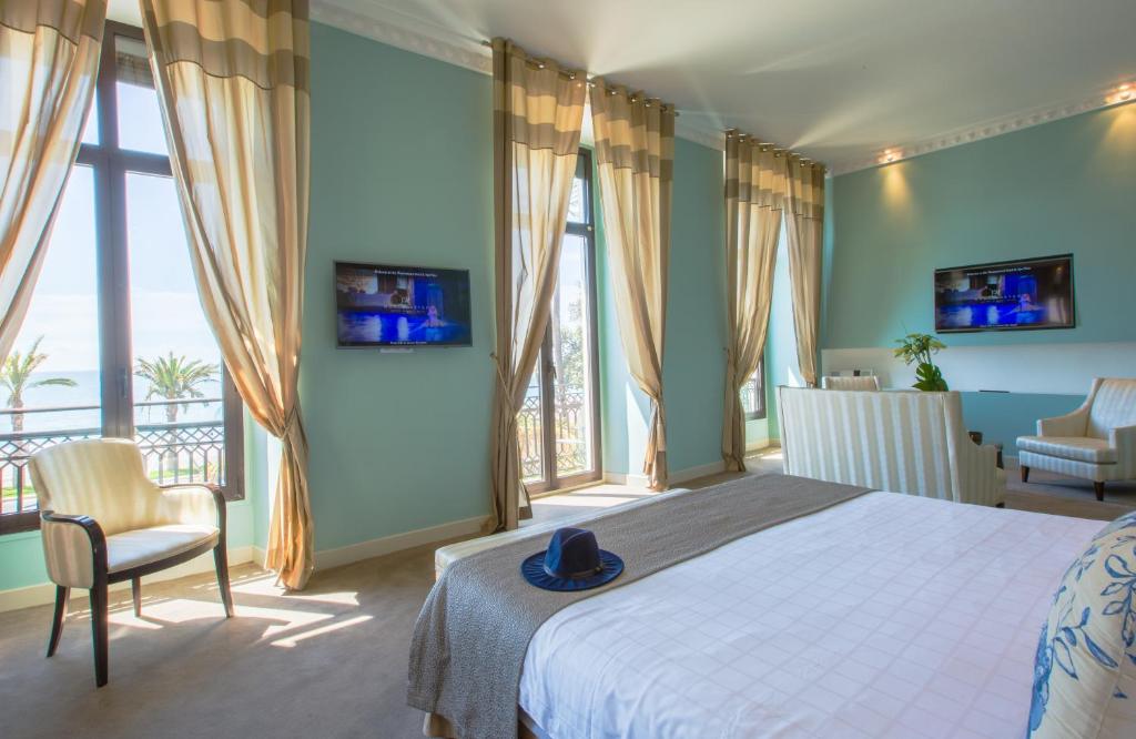 a bedroom with a large bed and large windows at Westminster Hotel & Spa Nice in Nice