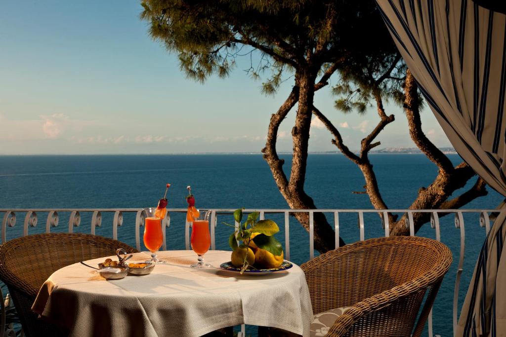 a table with drinks and fruit on a balcony with the ocean at Le Querce Resort Sea Thermae & Spa in Ischia