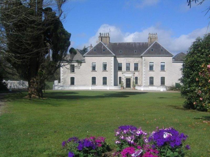 a large white house with flowers in the yard at Rathaspeck Manor B&B in Wexford