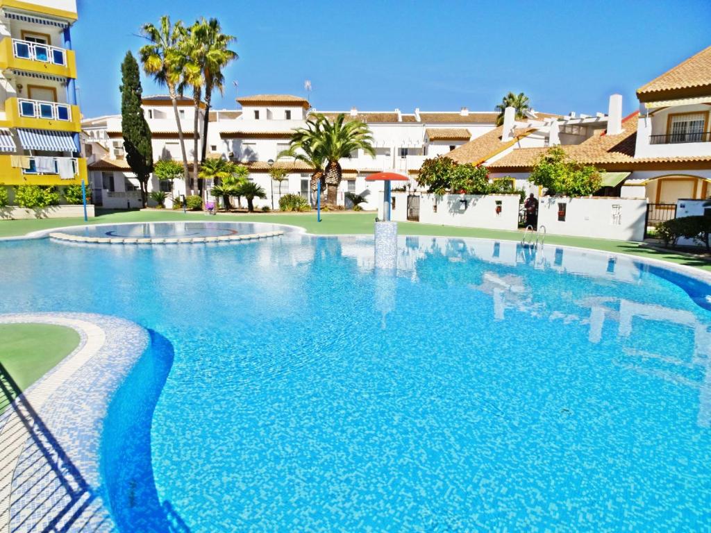 une grande piscine bleue avec des bâtiments en arrière-plan dans l'établissement SAN FERNANDO 40 - A 100 metros de la Playa, à Oliva