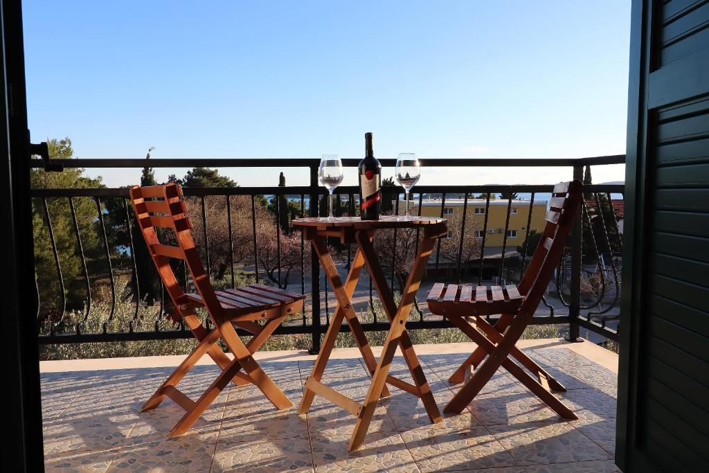 a table with two chairs and wine glasses on a balcony at Apartments Trstenica in Orebić
