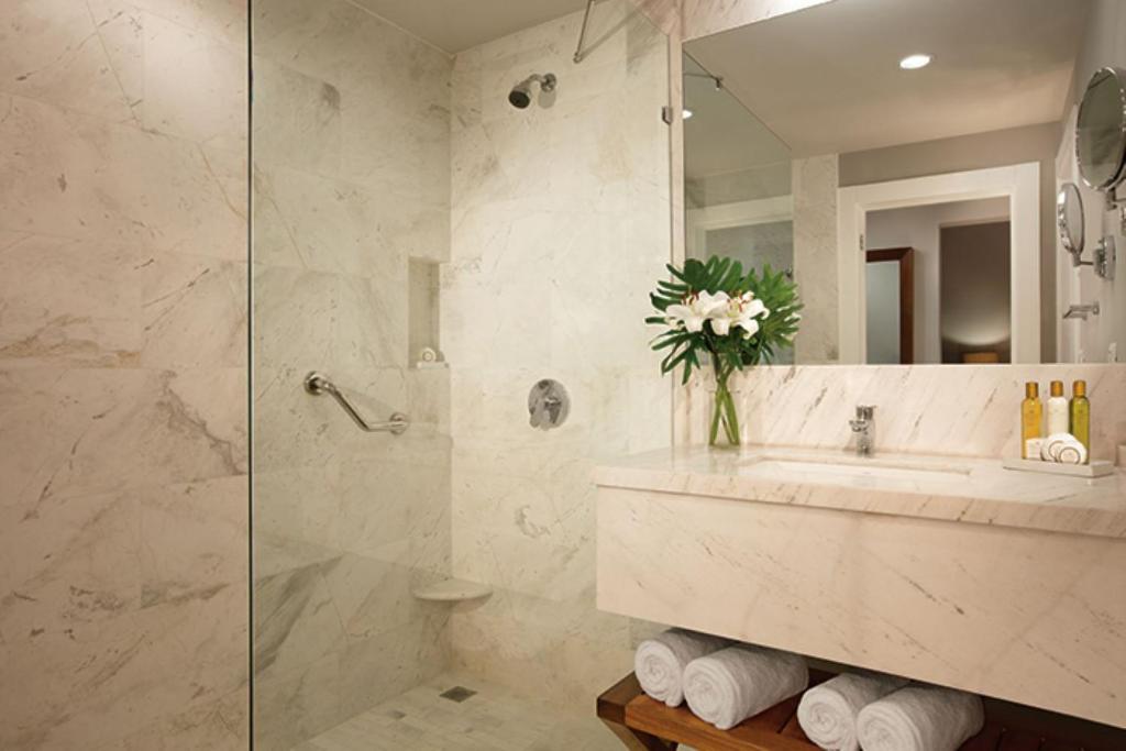 a bathroom with a sink and a shower with a mirror at Dreams Dominicus La Romana Resort & Spa in Bayahibe