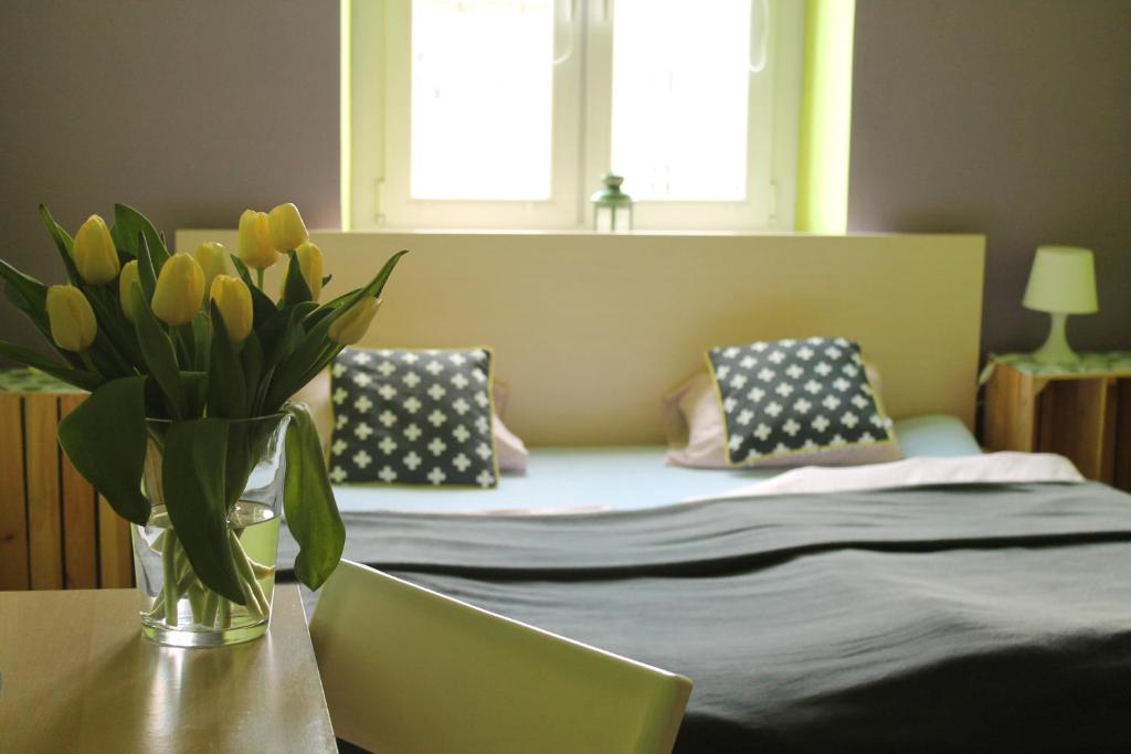 a bedroom with a bed with a vase of flowers on a table at Hostel Centrum Sabot in Krakow