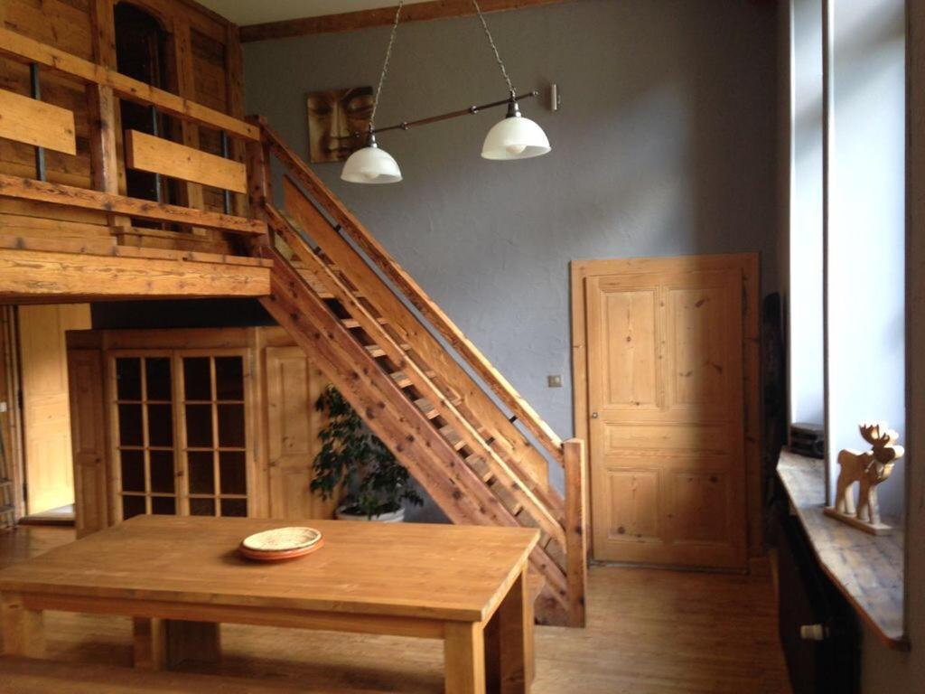a room with a wooden staircase and a wooden table at Ancienne école du Mont in Servoz