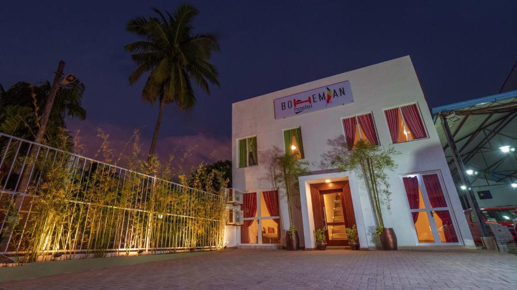 a white building with a palm tree in the night at Bohemian Hotel - Negombo in Negombo
