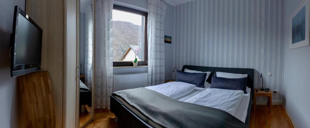 a bedroom with a bed with blue pillows and a window at Ferienwohnungen Haus am Würzlaysteig in Lehmen