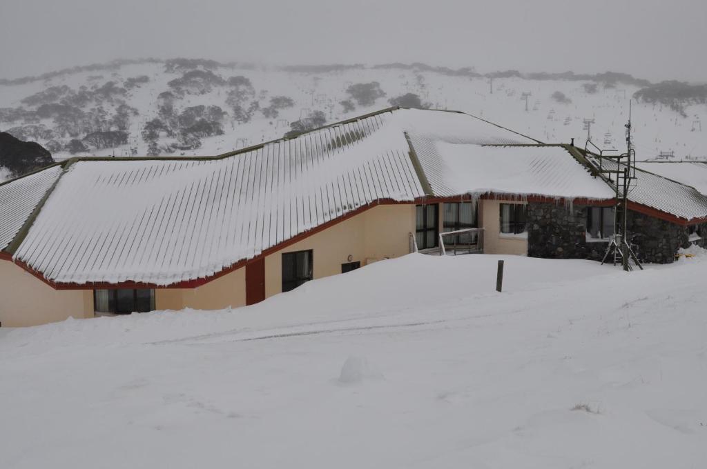 a house covered in snow with a mountain in the background at Salzburg Apartments in Perisher Valley