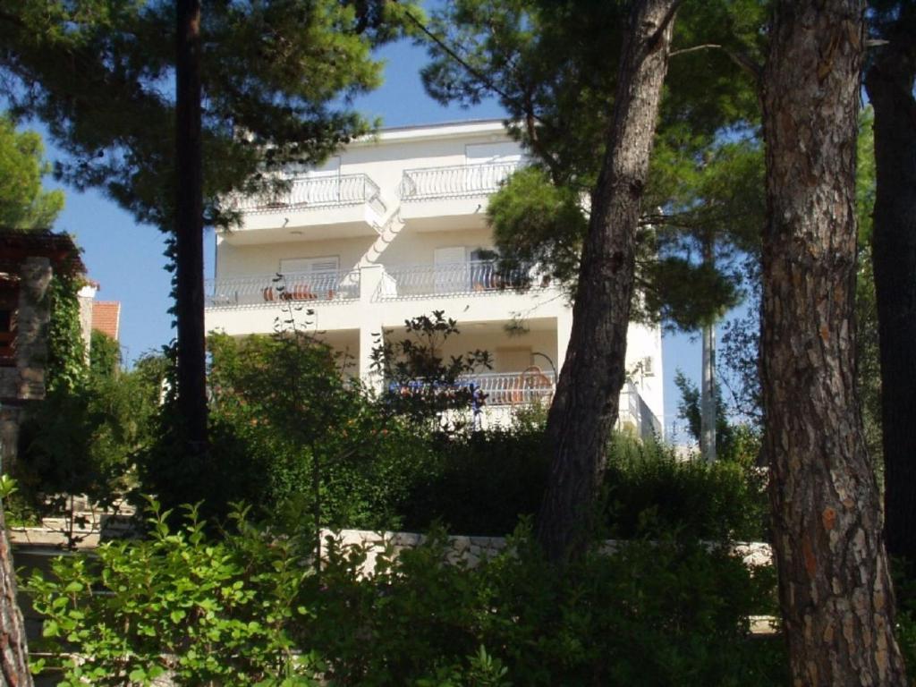 un edificio blanco con árboles delante de él en Villa Fendi, en Nečujam