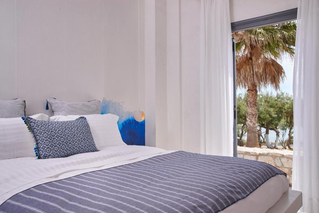 a bedroom with a bed and a window with a palm tree at Parian Boutique Hotel in Naousa