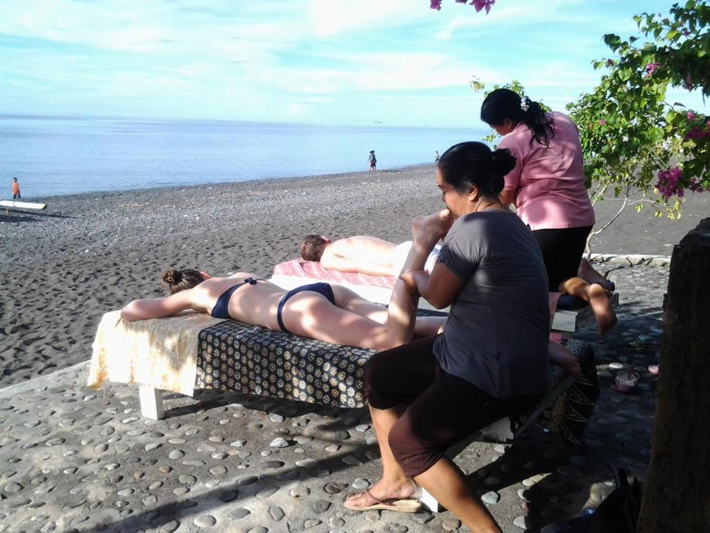a group of people laying on a bed on the beach at Solaluna Beach Homestay in Amed