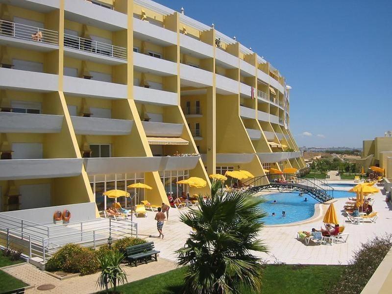 een groot geel gebouw met een zwembad en een resort bij Condomínio do Mar in Lagos