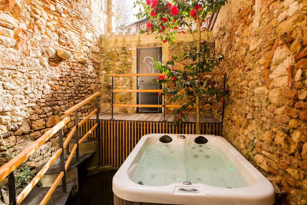 a bathroom with a bath tub in a stone wall at Appartement de charme au coeur de Bergerac in Bergerac