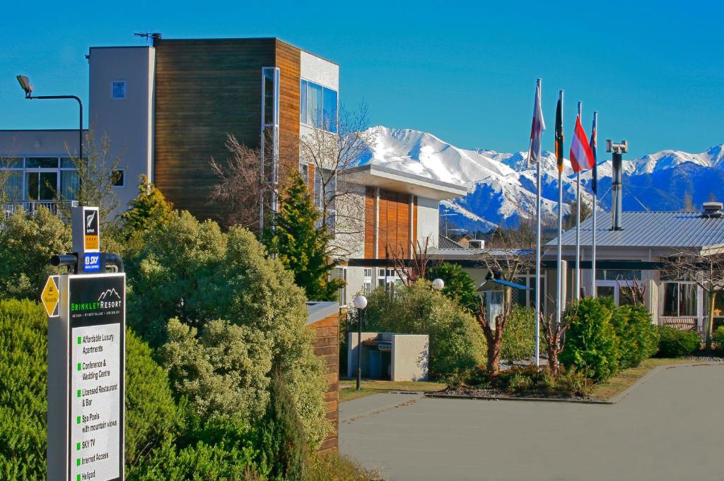 a sign in front of a building with snow covered mountains at Brinkley Resort in Methven