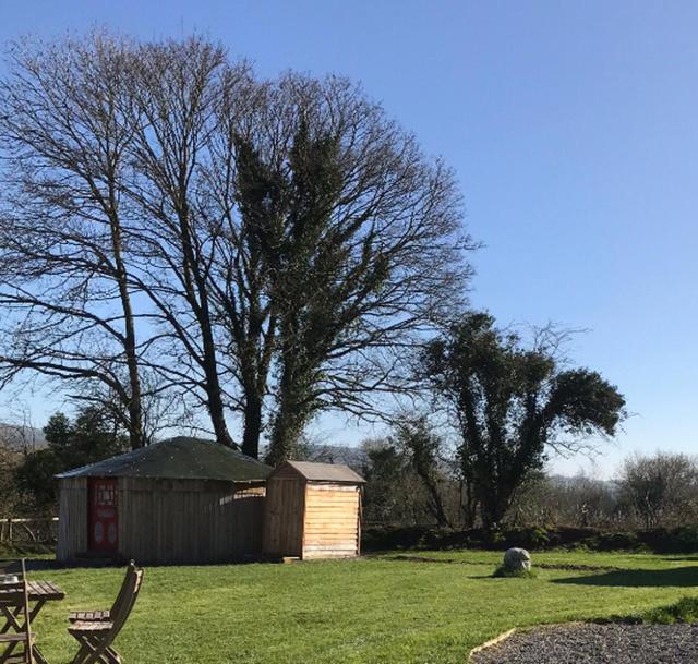 a shed and a bench in a grass field at McClure Yurt at Carrigeen Glamping in Kilkenny